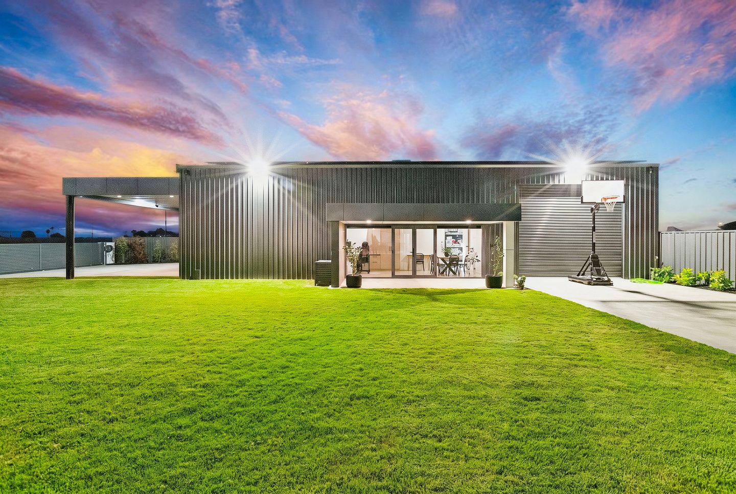 Shed and glazed office facing the lawn at twilight
